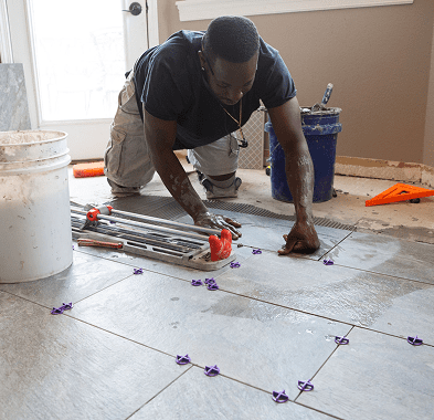 Person installing tiles on a floor.